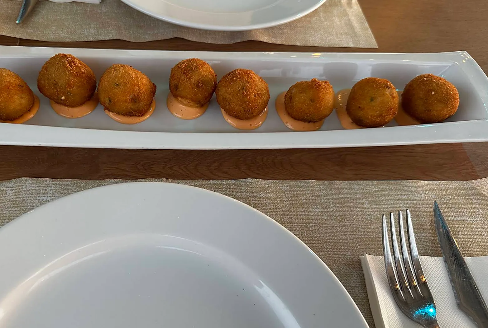 Fuente alargada con ocho croquetas sobre salsa rosa