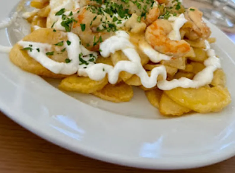 Patatas fritas en rodajas con gambas, alioli y perejil