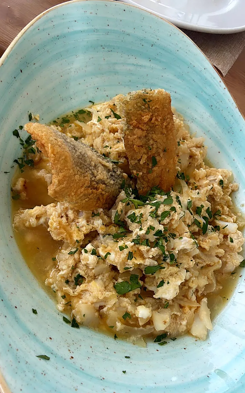 Revuelto de pescado con pieles crujientes y perejil en plato azul